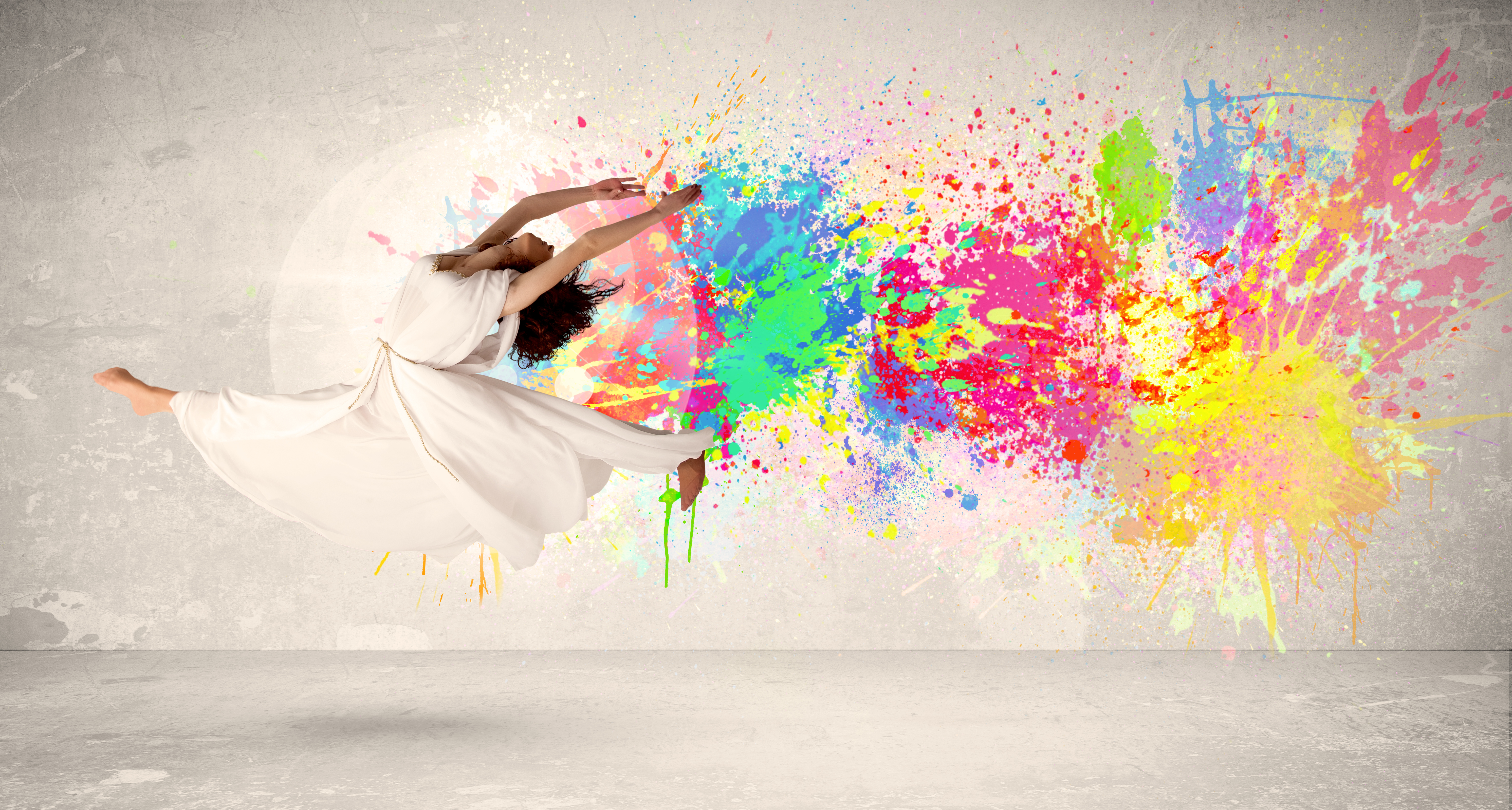 Happy teenager jumping with colorful ink splatter on urban background 